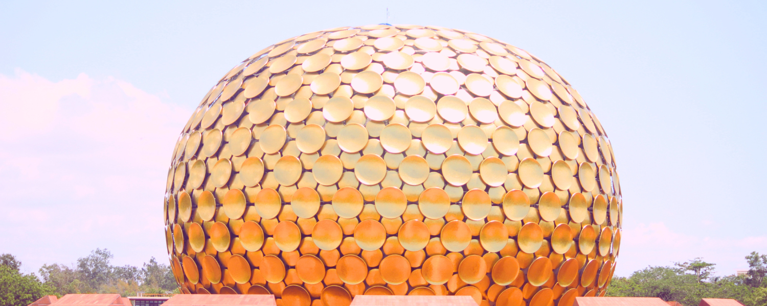 The Matrimandir, a large golden spherical structure, stands prominently against a clear blue sky in Auroville, Pondicherry.